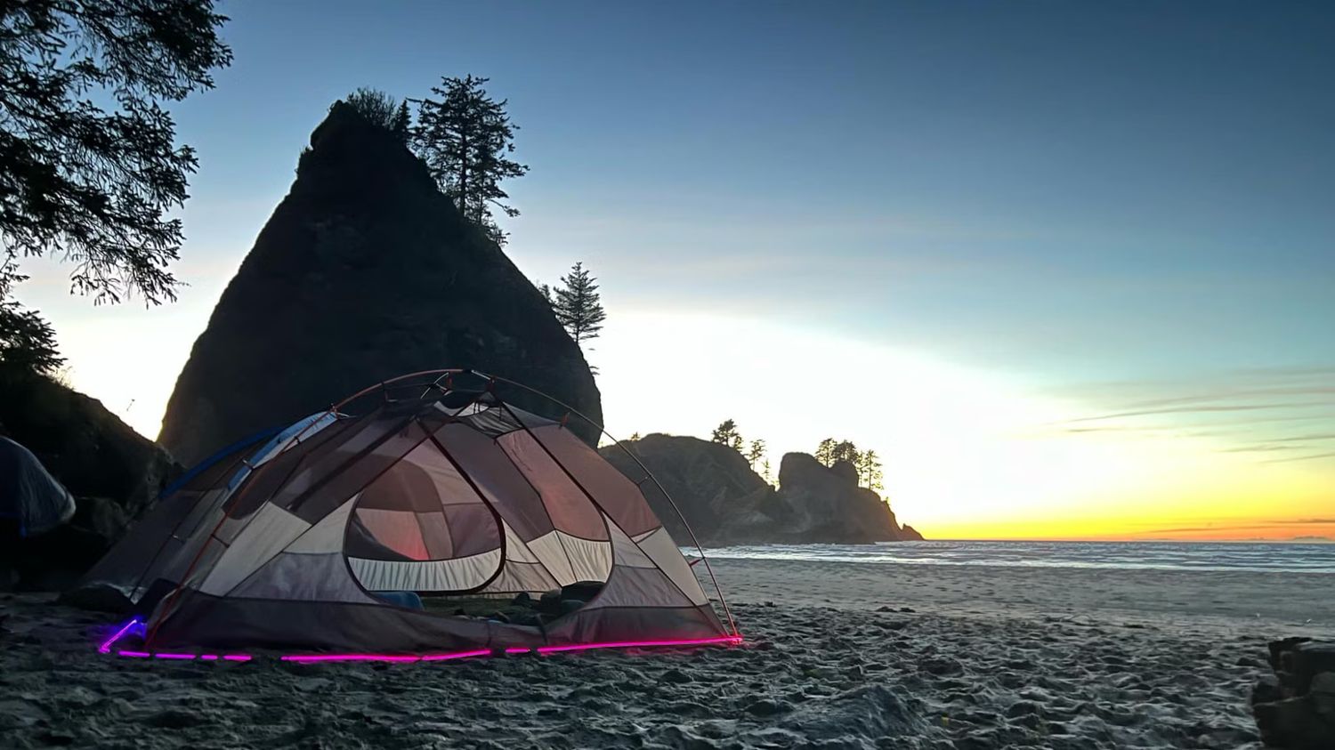 A tent on a beach at sunset outlined in glowing magenta Trippy Wire.